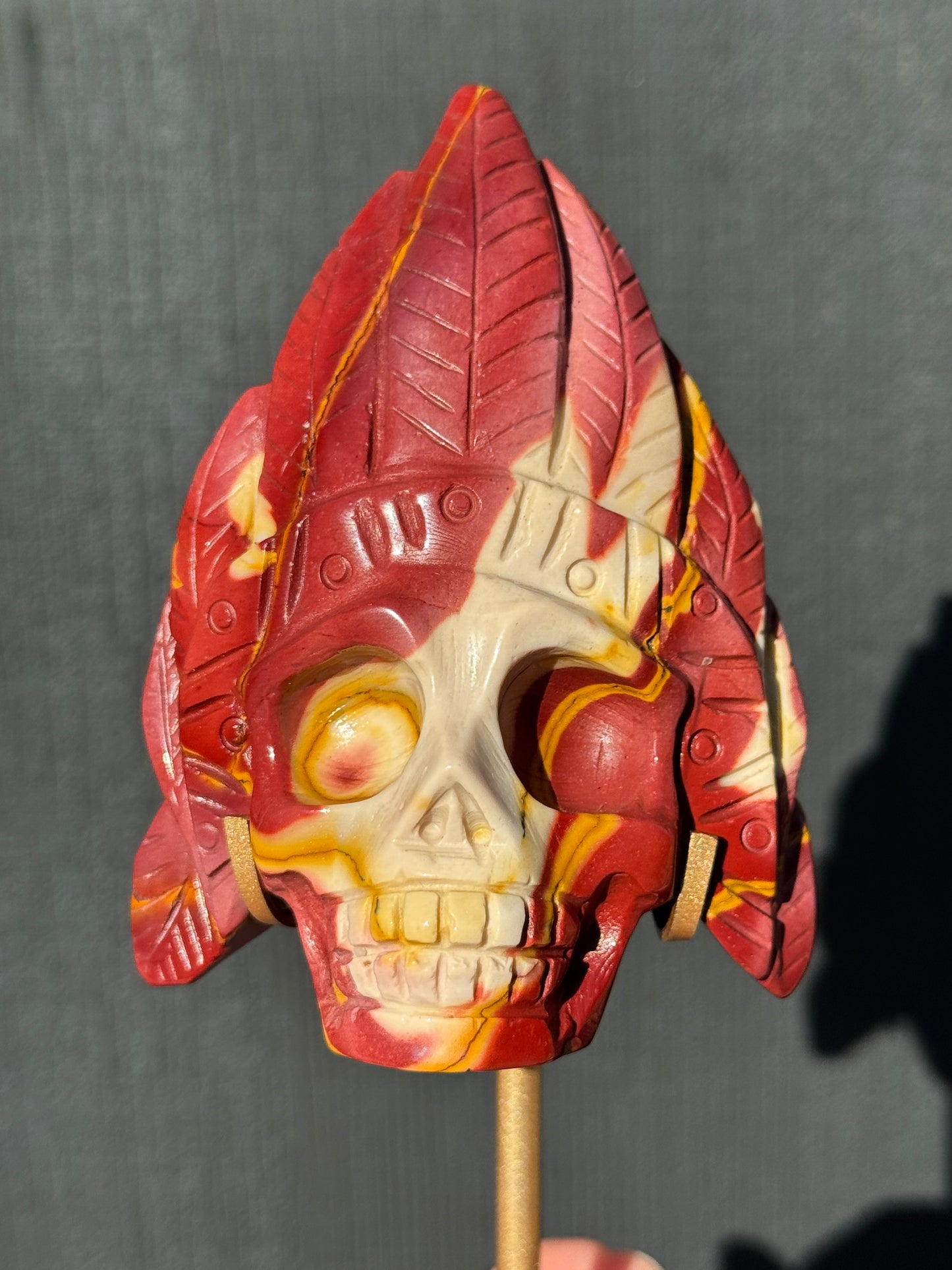 Mookaite Jasper carved Skull with Feathers on a stand