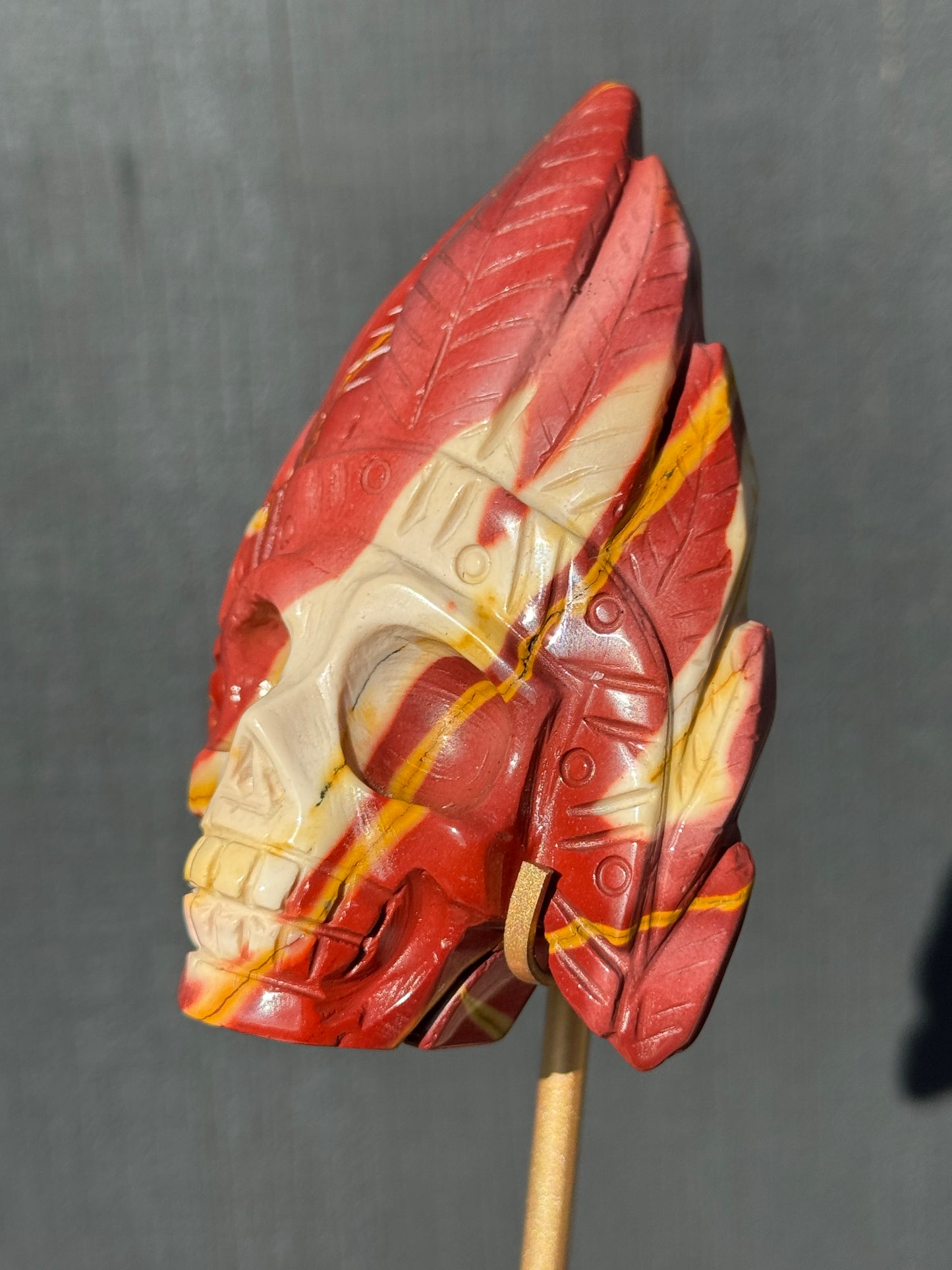 Mookaite Jasper carved Skull with Feathers on a stand