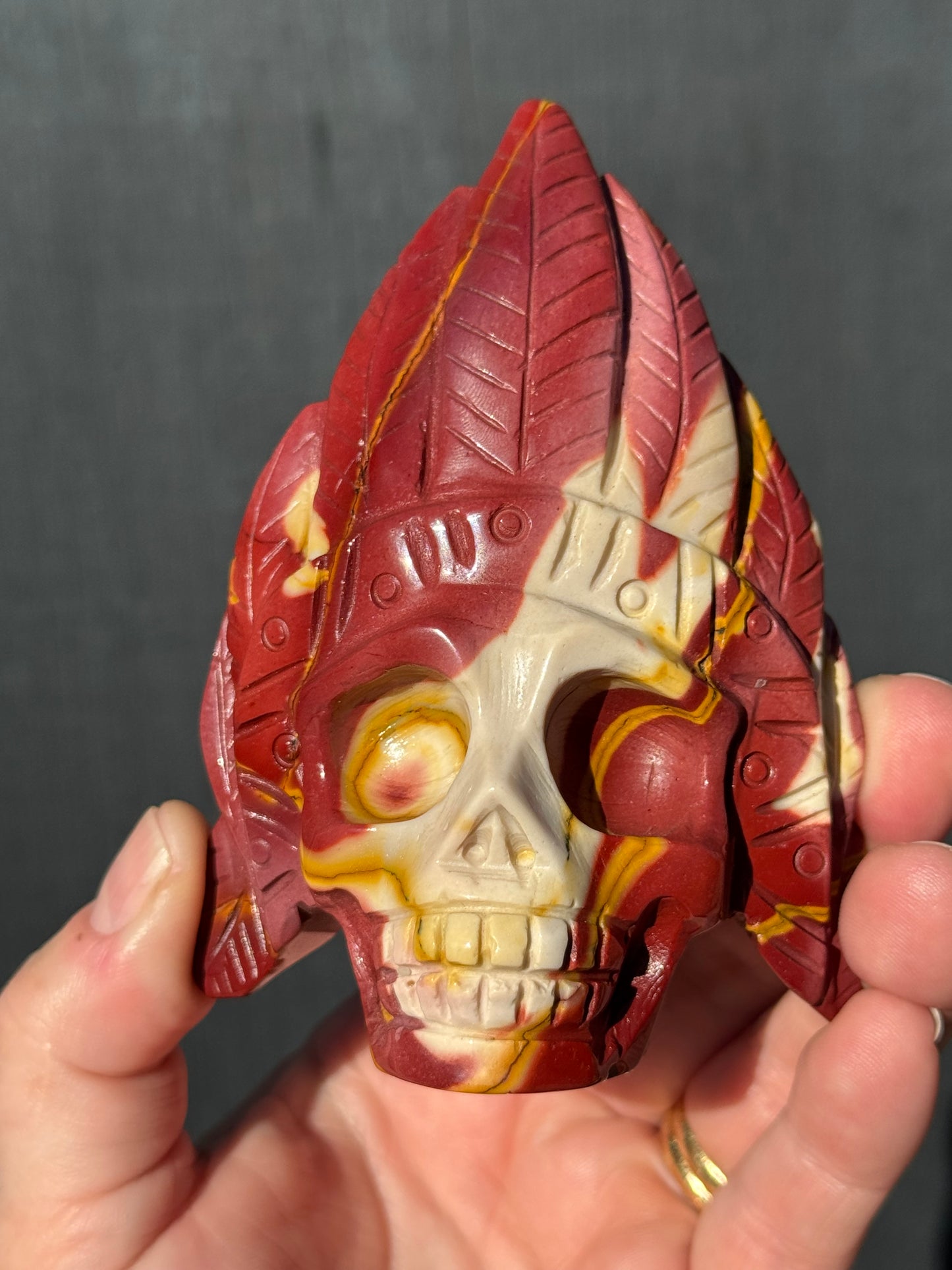 Mookaite Jasper carved Skull with Feathers on a stand