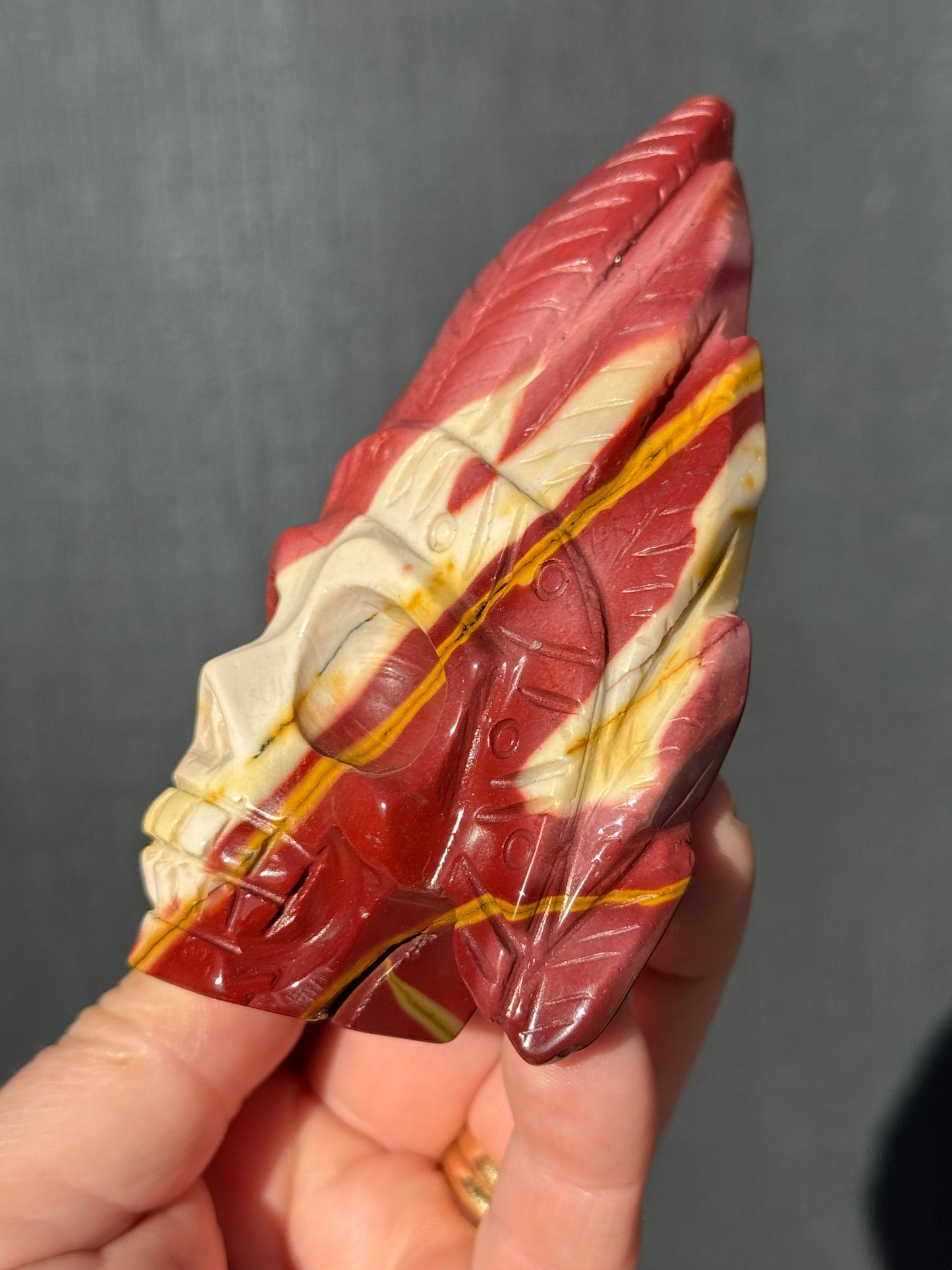 Mookaite Jasper carved Skull with Feathers on a stand