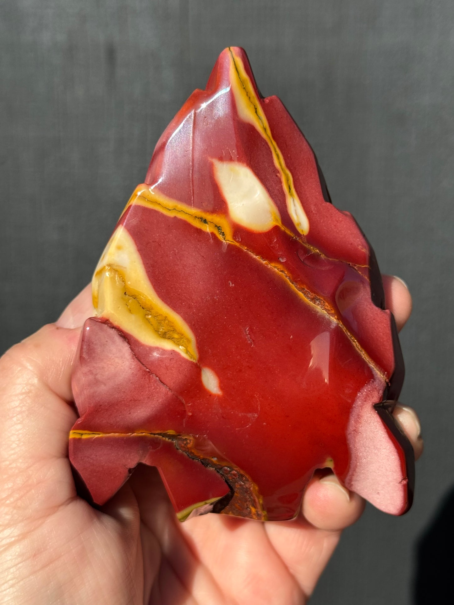 Mookaite Jasper carved Skull with Feathers on a stand