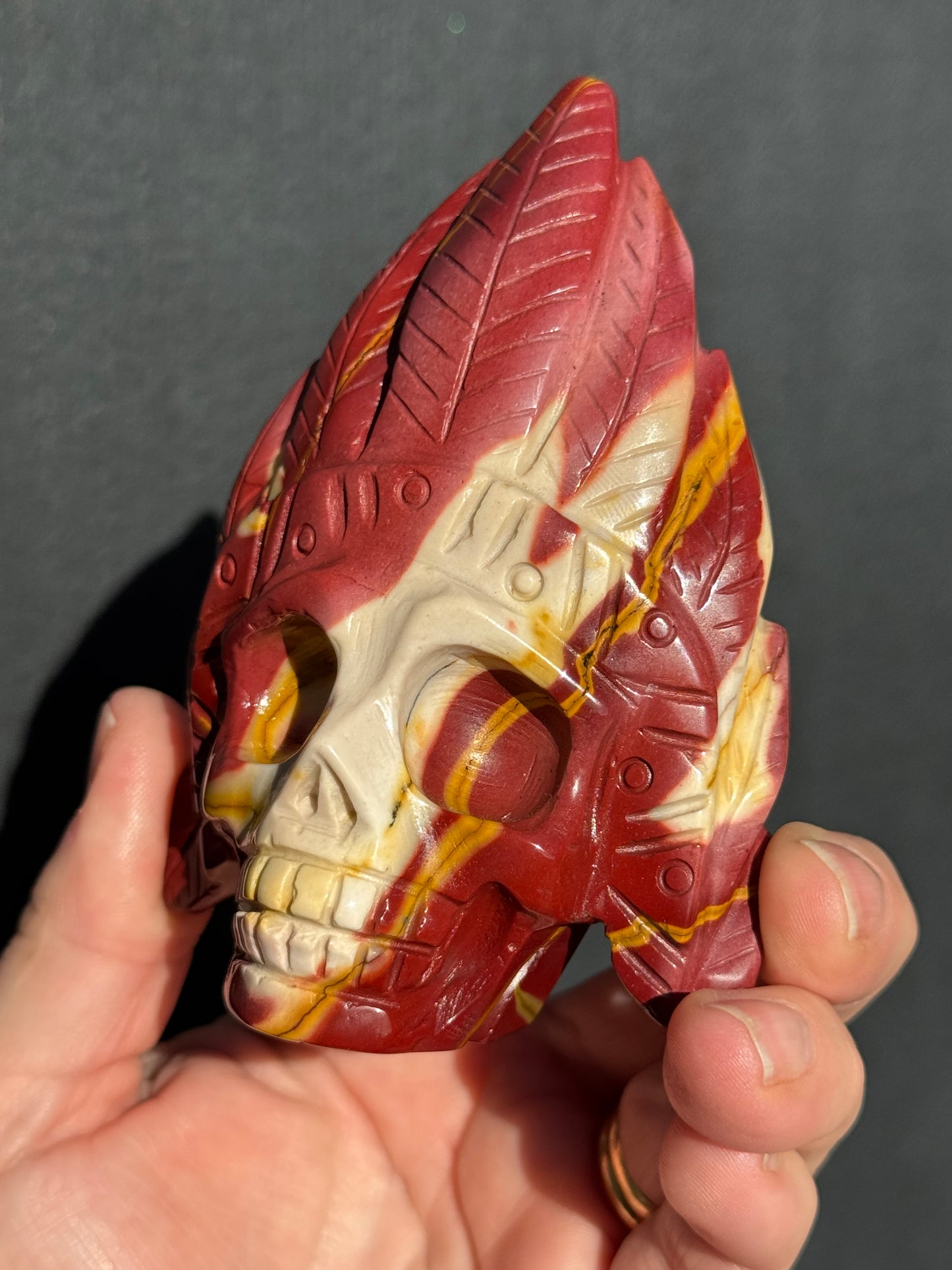 Mookaite Jasper carved Skull with Feathers on a stand