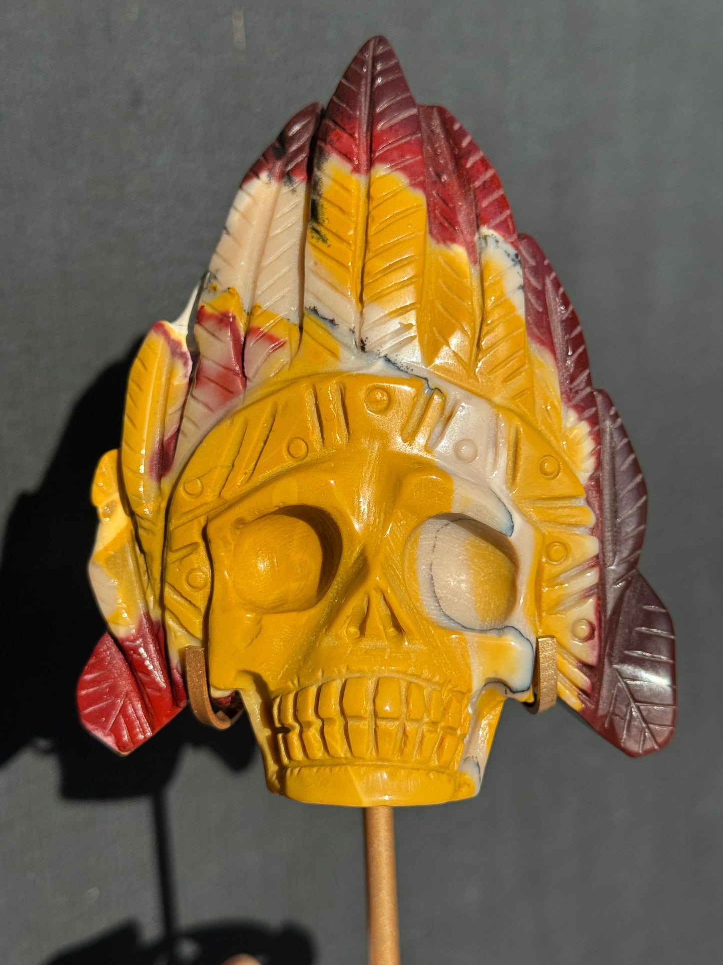 Mookaite Jasper carved Skull with Feathers on a stand