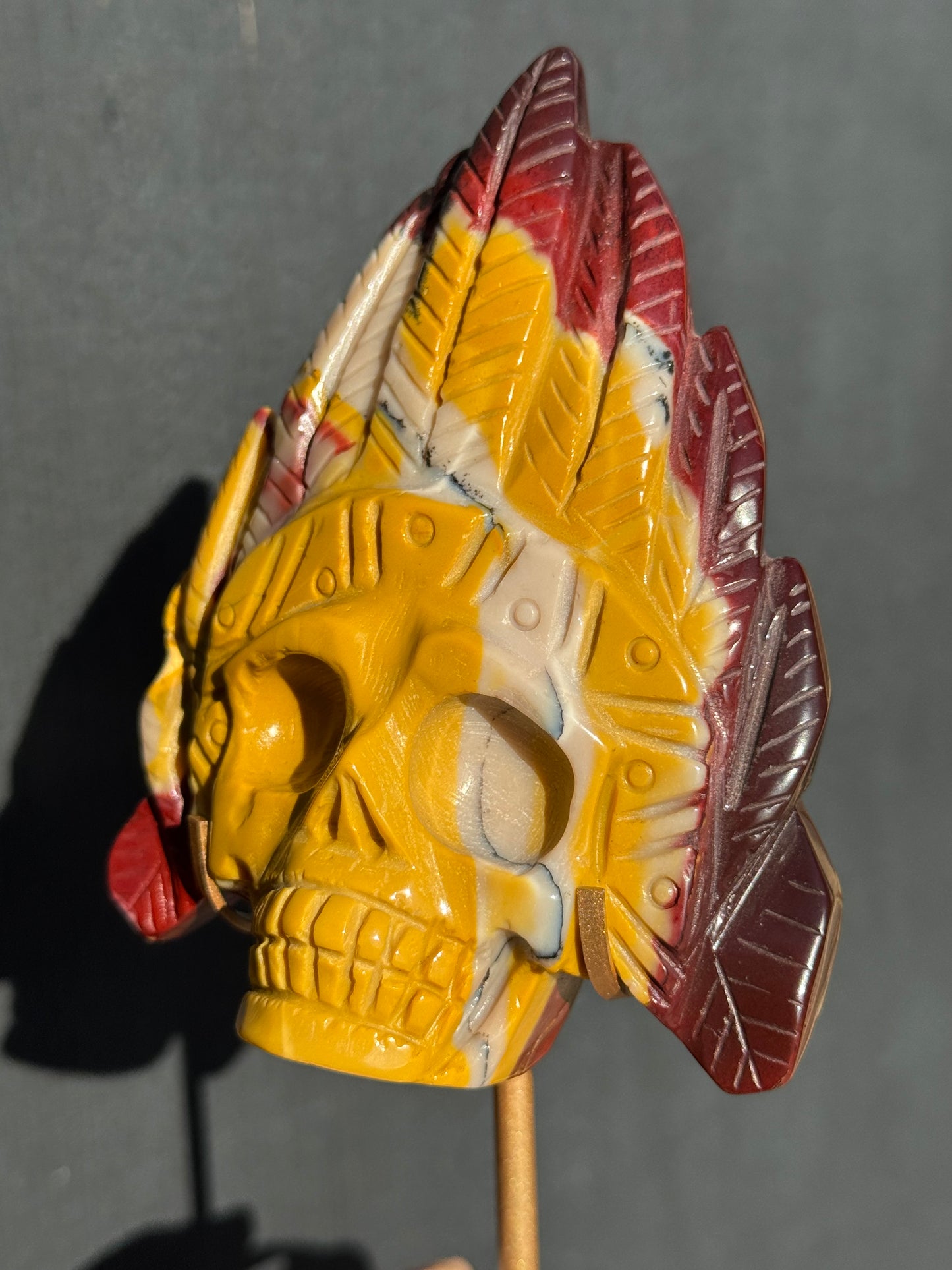 Mookaite Jasper carved Skull with Feathers on a stand