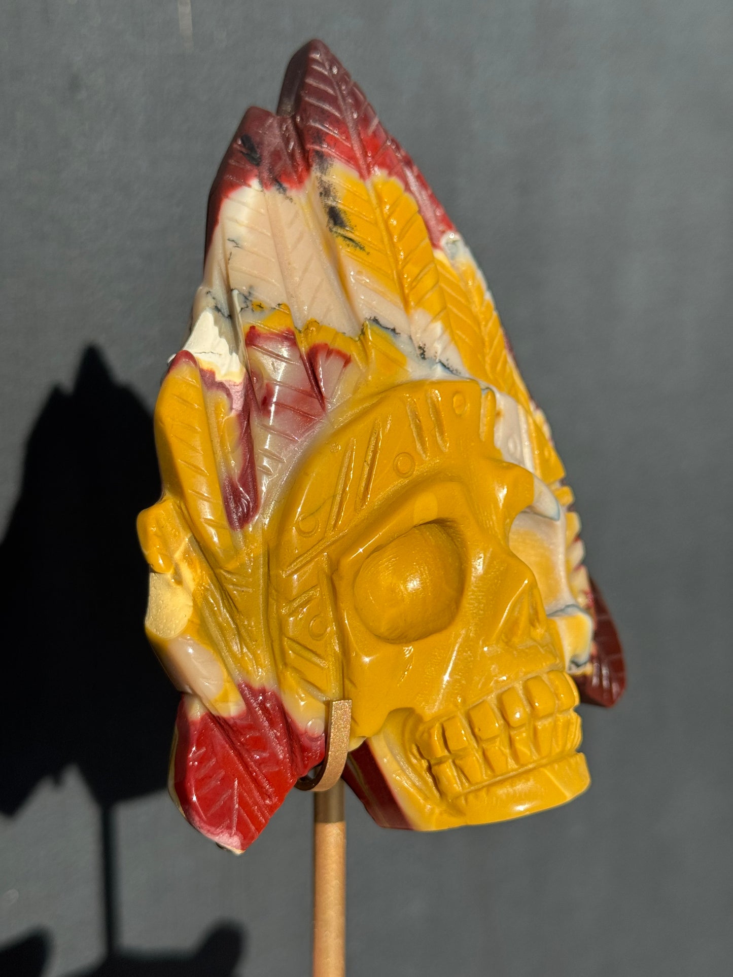 Mookaite Jasper carved Skull with Feathers on a stand