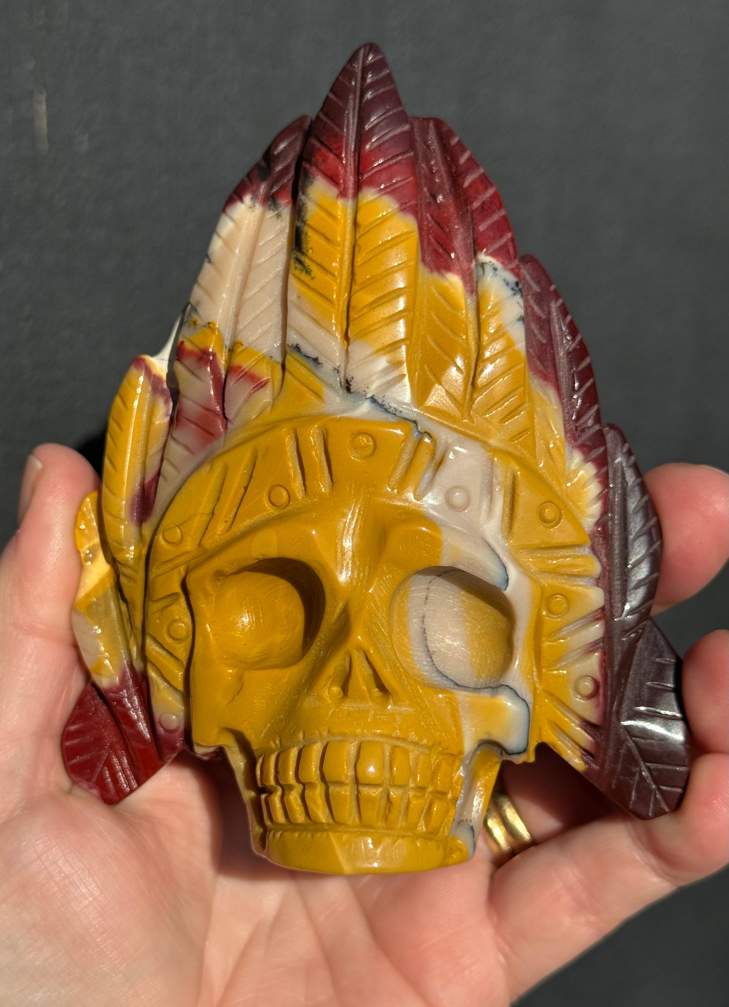 Mookaite Jasper carved Skull with Feathers on a stand