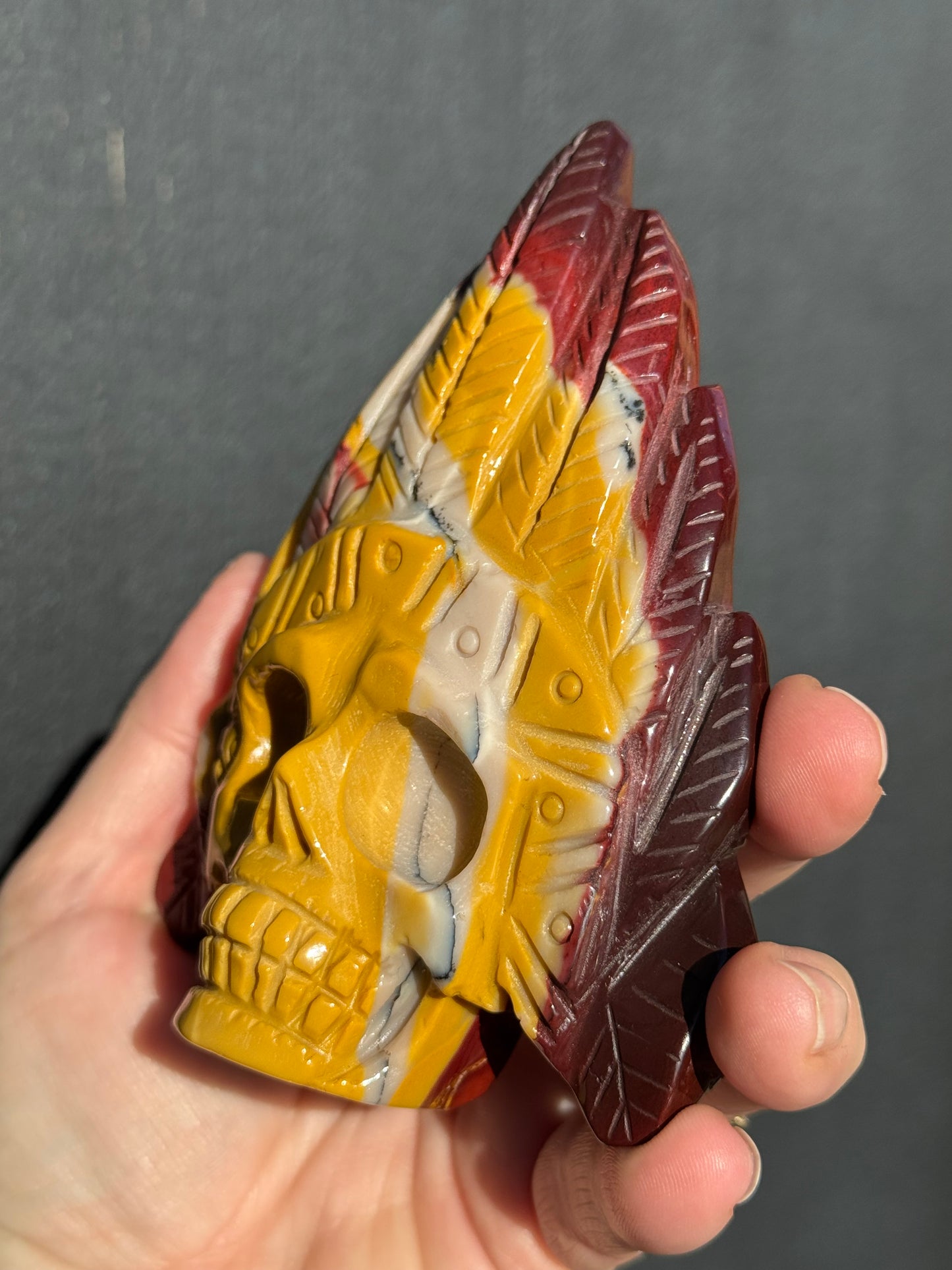 Mookaite Jasper carved Skull with Feathers on a stand