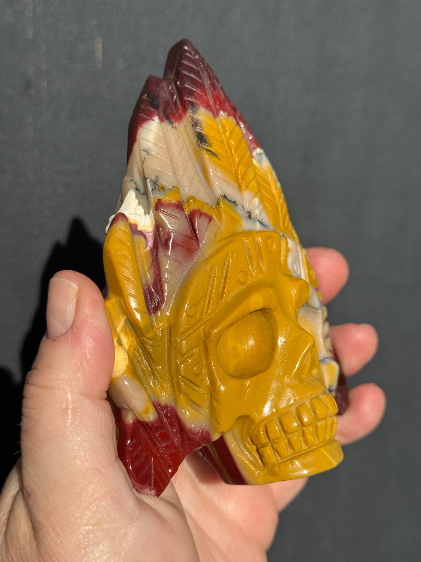 Mookaite Jasper carved Skull with Feathers on a stand