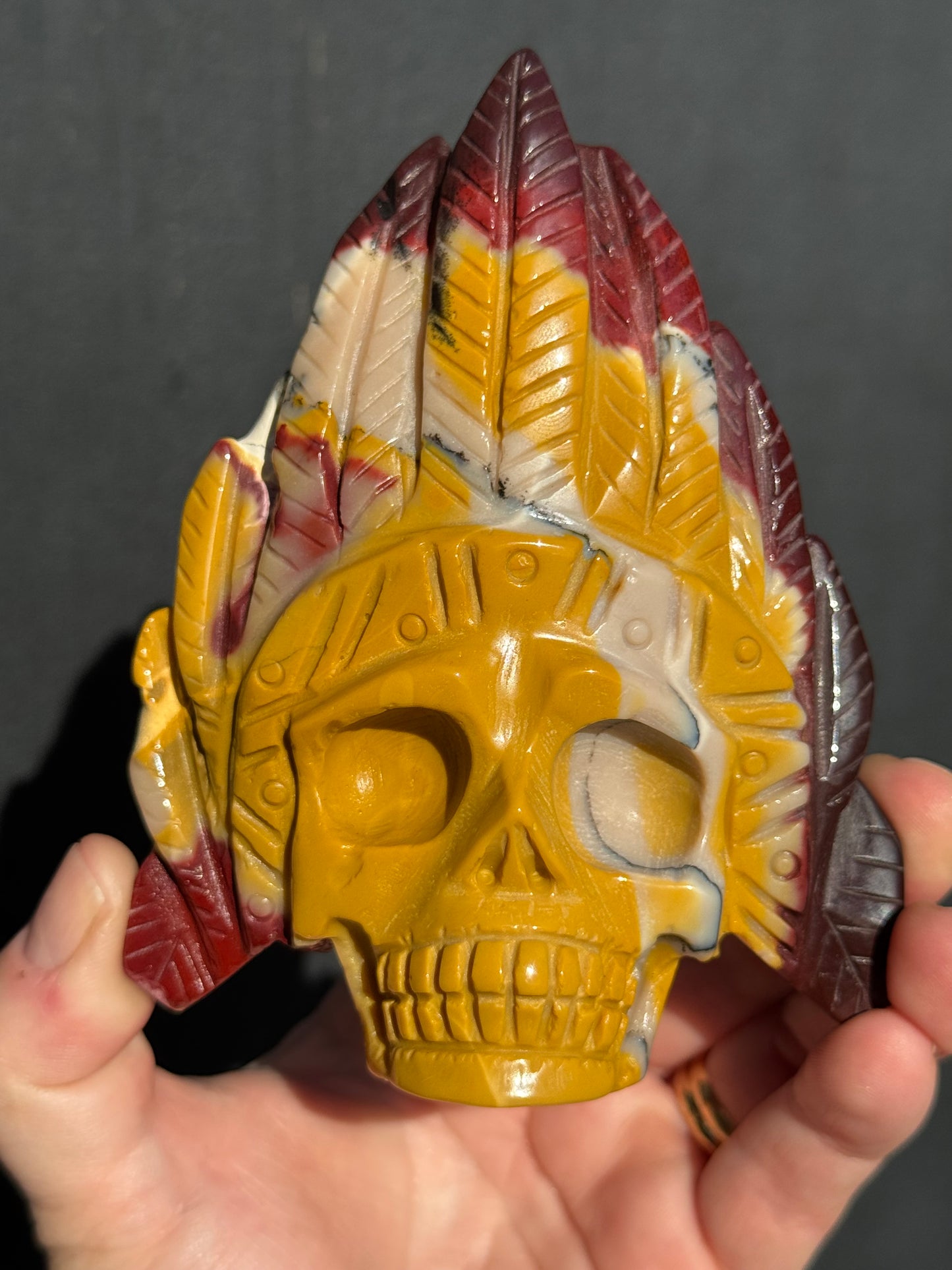 Mookaite Jasper carved Skull with Feathers on a stand