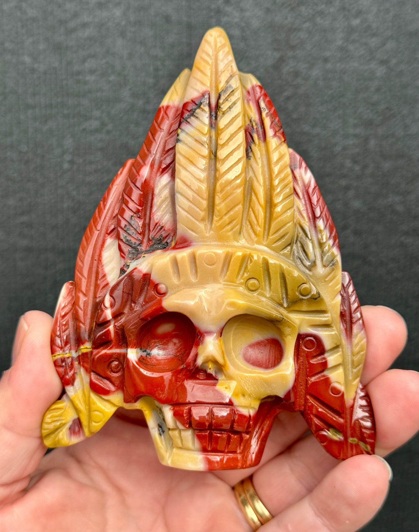 Mookaite Jasper carved Skull with Feathers on a stand