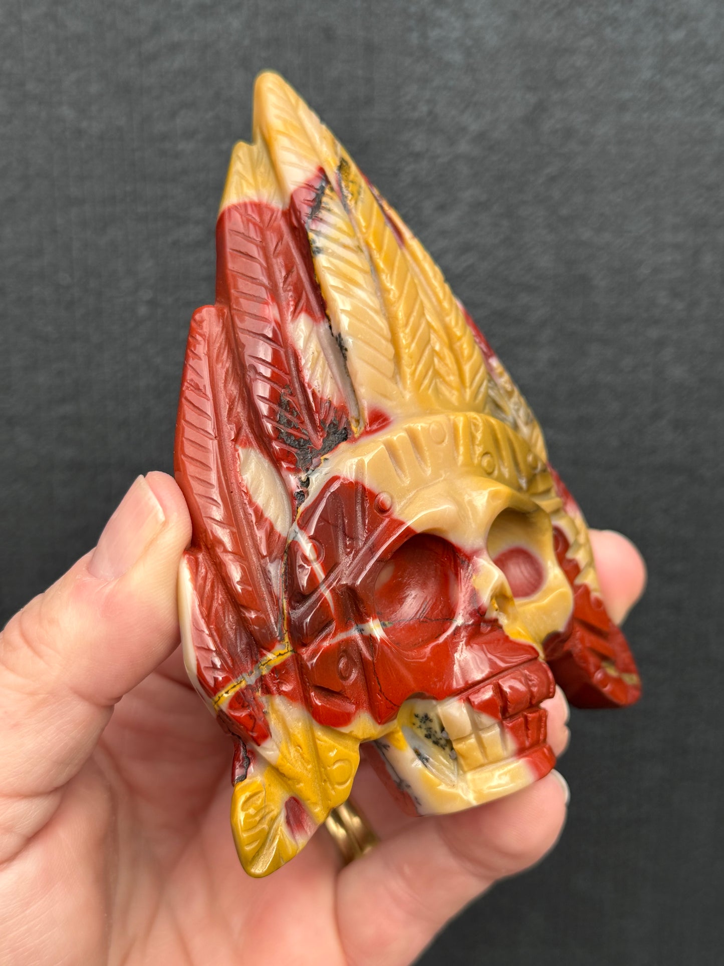 Mookaite Jasper carved Skull with Feathers on a stand