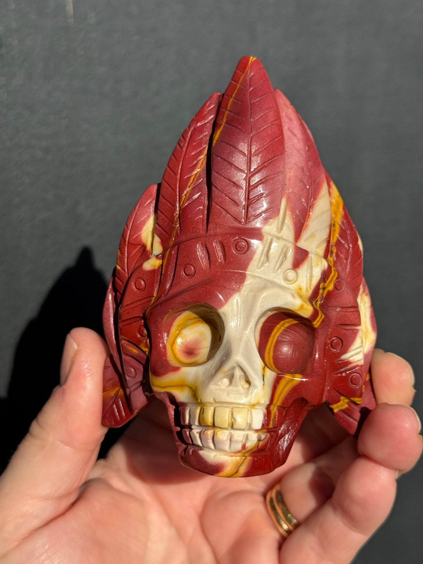 Mookaite Jasper carved Skull with Feathers on a stand